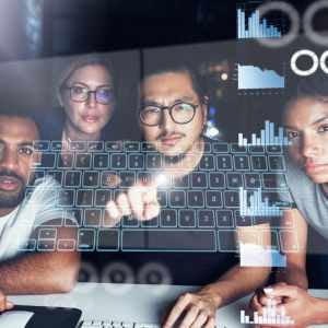 4 people looking at a screen with graphs and an onscreen keyboard