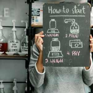 a person in a bulk store holding up a guide on how to fill containers