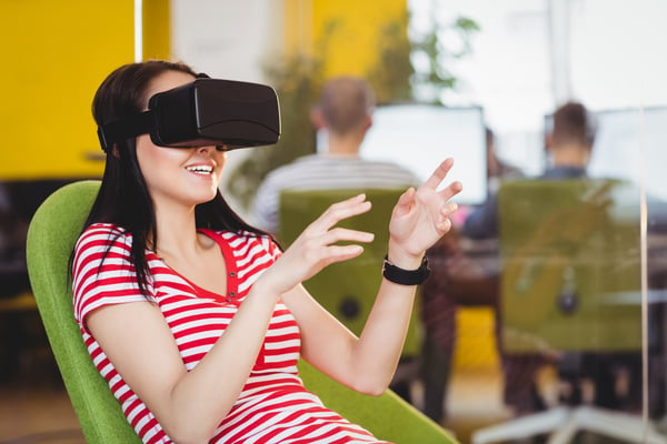 Happy young female executive enjoying augmented reality glasses at creative office-1