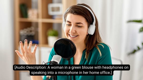[Audio Description A woman in a green blouse with headphones on speaking into a microphone in her home office.]