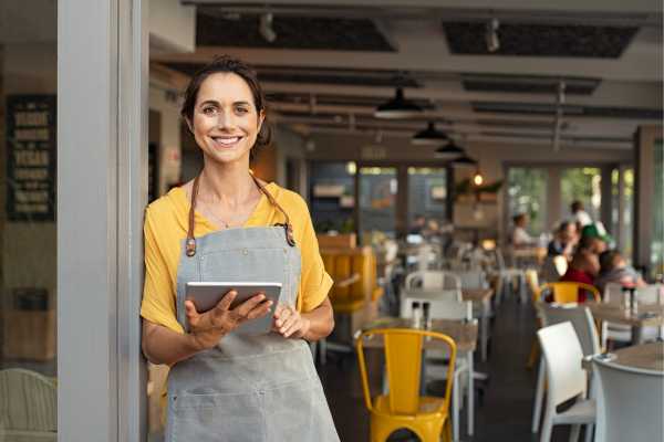 a female waitress in a near empty cafe smiling towards the camera
