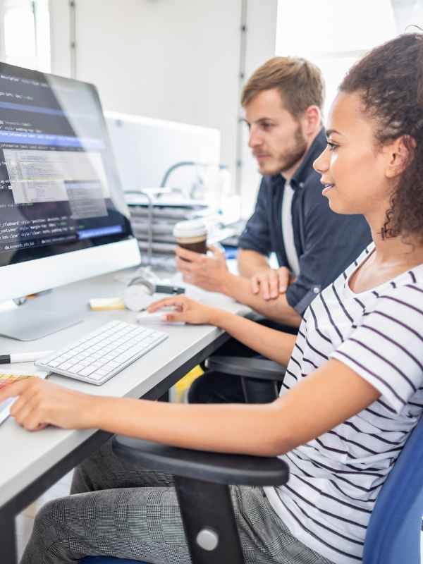 a man and a woman working together looking at a monitor with code