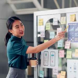 a women pointing to a mockup on a clear board with pieces of design on it