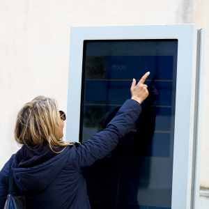 a-women-stretching-to-reach-the-top-option-on-a-digital-kiosk