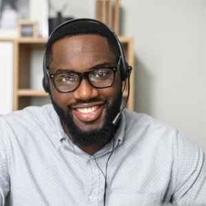 a_man_smiling_at_the_camera_wearing_glasses_and_a_headset