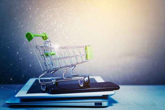 a_store_shopping_cart_on_top_of_a_pile_of_electronic_devices_including_a_laptop_and_a_tablet_and_a_mobile_phone