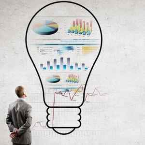 gray-background-with-a-man-facing-a-wall-looking-at-a-lightbulb-drawn-on-it-with-charts-and-graphs-in-it