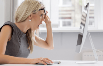 Woman looking at her computer, with a surprised and appalled expression